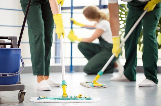 Trije čistilci čistilnega servisa čistijo tla.
