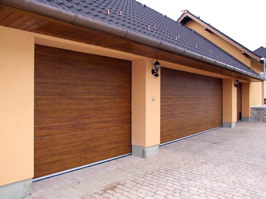 Dvoje dvižnih garažnih vrat z lesenim vzorcem na tlakovanem dvorišču.