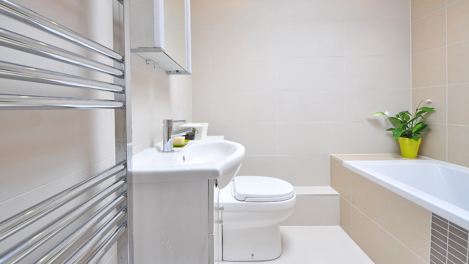 Moderna kopalnica v bež barvi z belo sanitarno opremo in kovinskim radiatorjem.