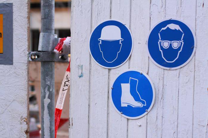 Modri znaki za priporočljivo nošnjo zaščitne čelade, zaščitnih očal in zaščitne obutve na gradbišču.