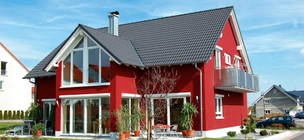 Živo rdeča hiša s sivo streho v predmestju.