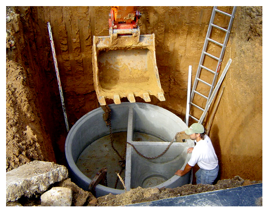 Globoka jama, v kateri je betonska čistilna naprava in moški, ki sodeluje pri montaži.