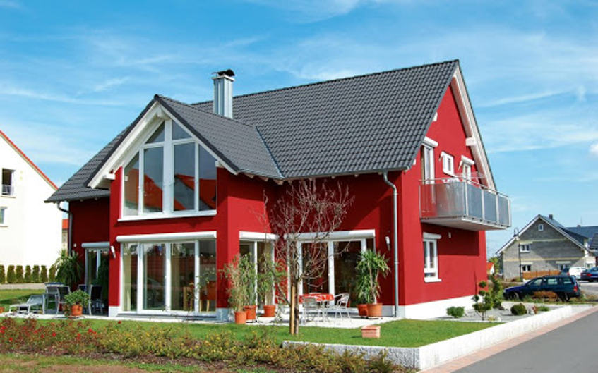Živo rdeča hiša s sivo streho v predmestju.