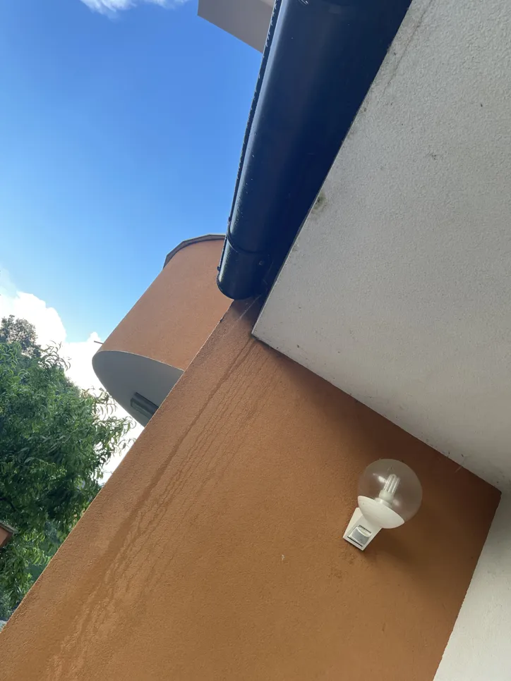 Visible water stains on an exterior wall beneath a black gutter, indicating a potential leakage issue.