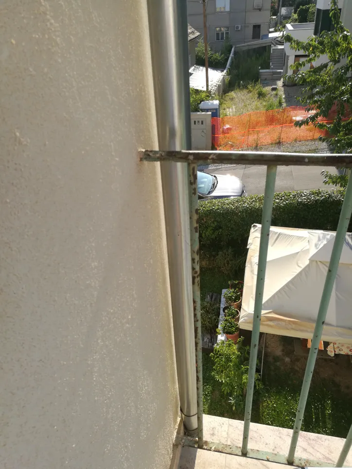 Close-up of a rusty balcony railing showing metal corrosion and deterioration.