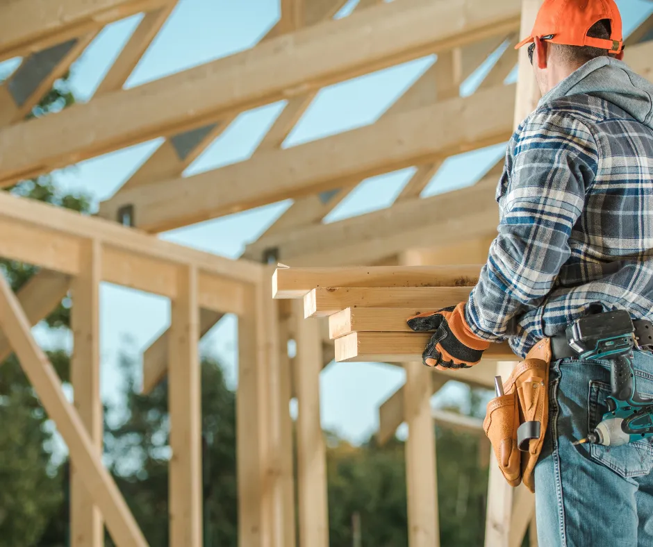 Skelet hiše in delavec z lesom v rokah