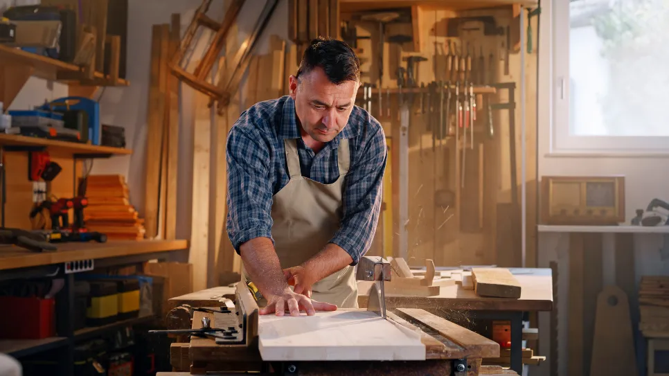 Mizar v svoji delavnici reže kos lesa.