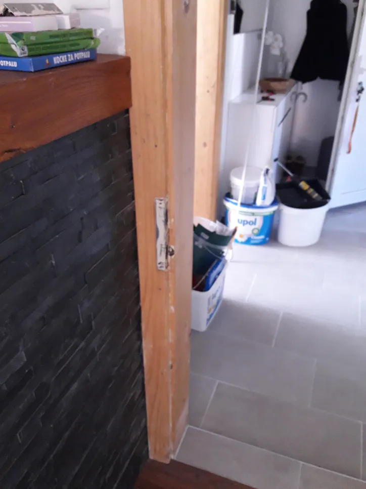 A door frame with visible damage and peeling paint, indicating potential structural issues.