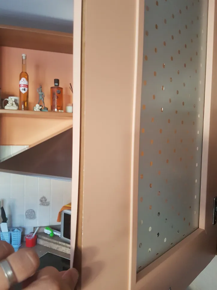 A kitchen cabinet door appears uneven and misaligned, indicating a need for hinge adjustment.