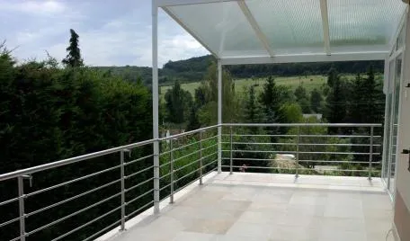Velik balkon na podeželju z nadstreškom in prečno inox ograjo