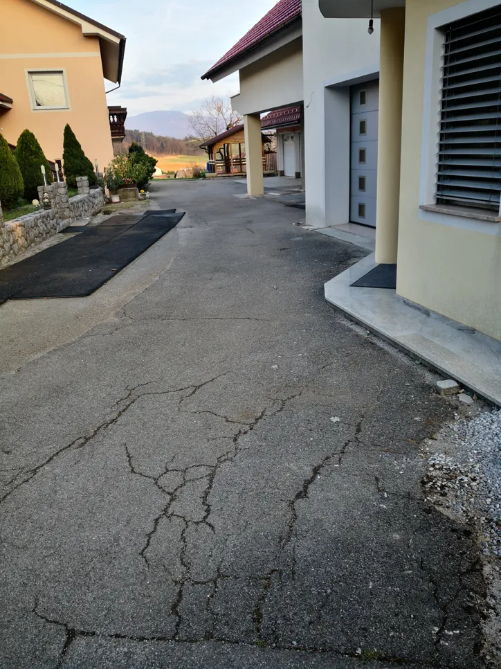 Cracked driveway surface indicating wear and potential for further damage, located outside a residential property.