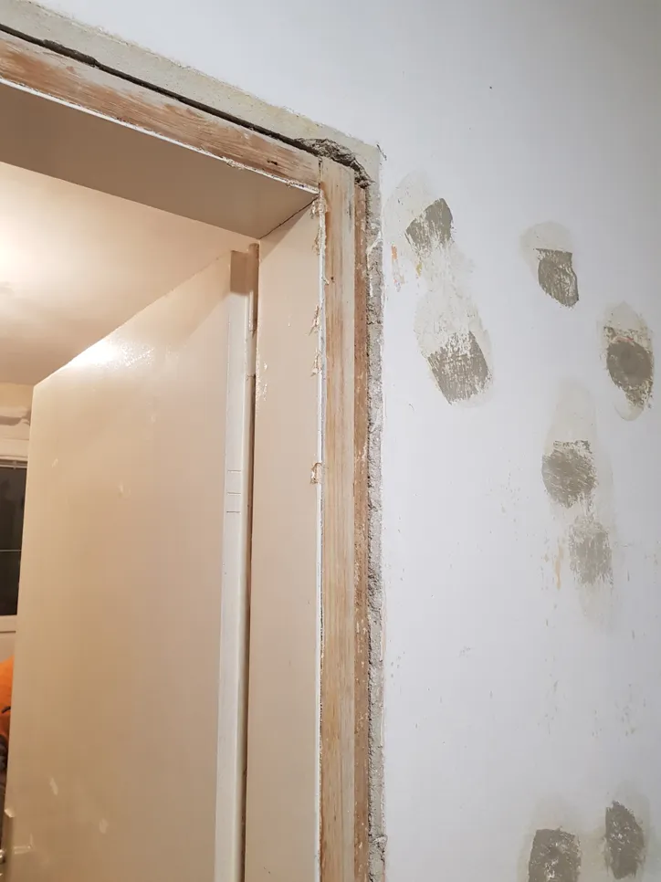 Door frame damage repair (53834) Damaged door frame with visible wood and wall repair marks. Ideal for addressing door frame repair needs.