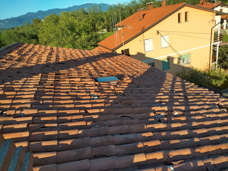 Broken roof tiles under sunlight highlight potential weather damage or wear.