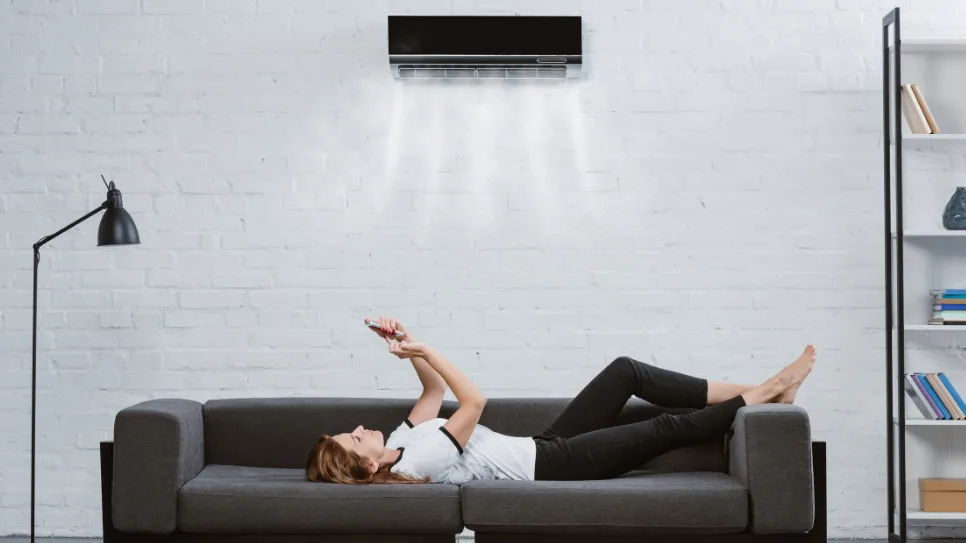 Dekle na kavču uravnava klimatsko napravo