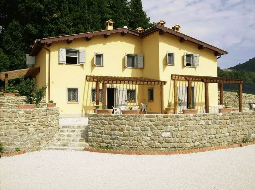 Hiša rumene barve s kamnito škarpo.