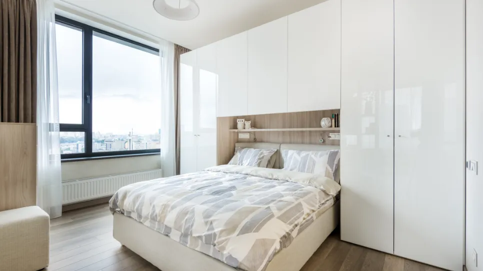 Bela vgradna omara v spalnici z leseno knjižno polico