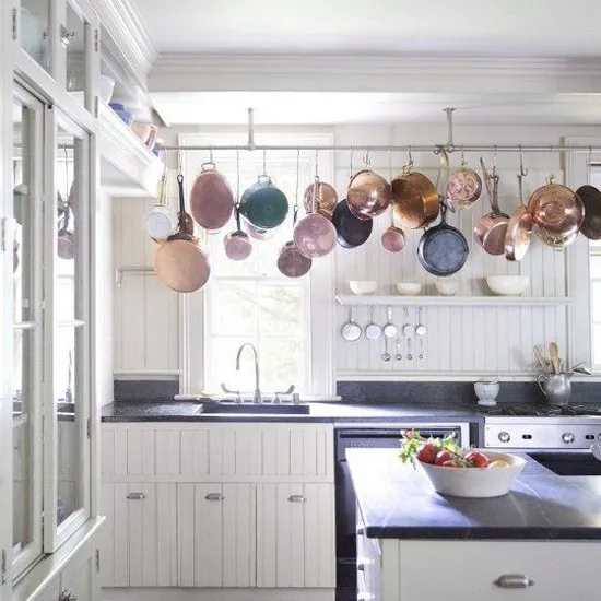 Kuhinja z obešenimi ponvami Obešene ponve in lonci v kuhinji.