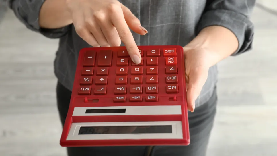 Oseba nam pred nos moli rdeč kalkulator.