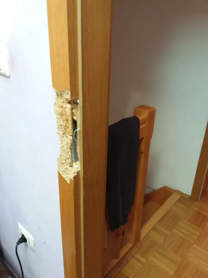 Damaged door frame repair (18905) Wooden door frame showing severe damage and chipping, requiring repair and restoration efforts.