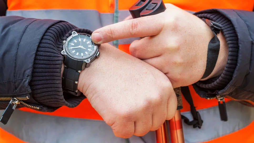 Delavec kaže na zapestno uro. Roki izvedbe za obrtniška dela so vse daljši.