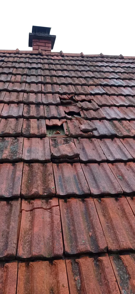 A damaged roof with broken tiles and visible wear showing potential water entry points.