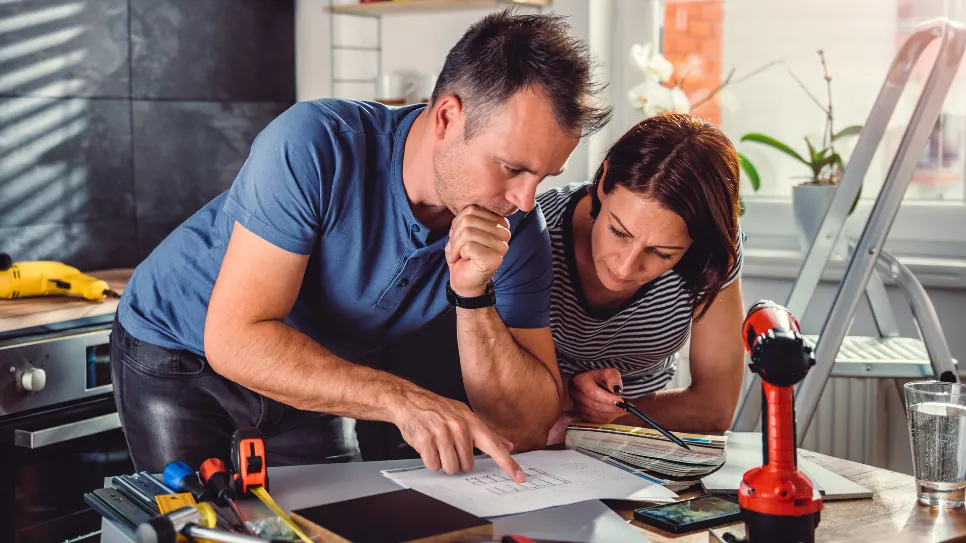 Par gleda načrte na mizi, medtem ko poteka prenova stanovanja.