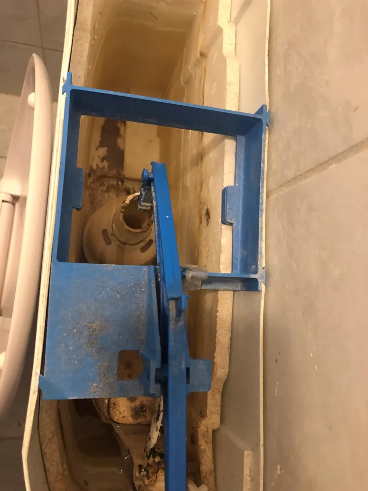 Toilet cistern with damaged components (36838) Open toilet cistern showing blue framework, sediment buildup, and disconnected parts causing issues.