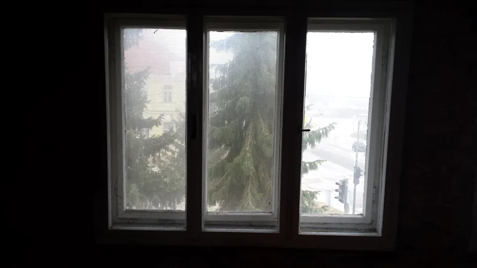 A drafty three-panel window with visible moisture buildup, affecting insulation efficiency.