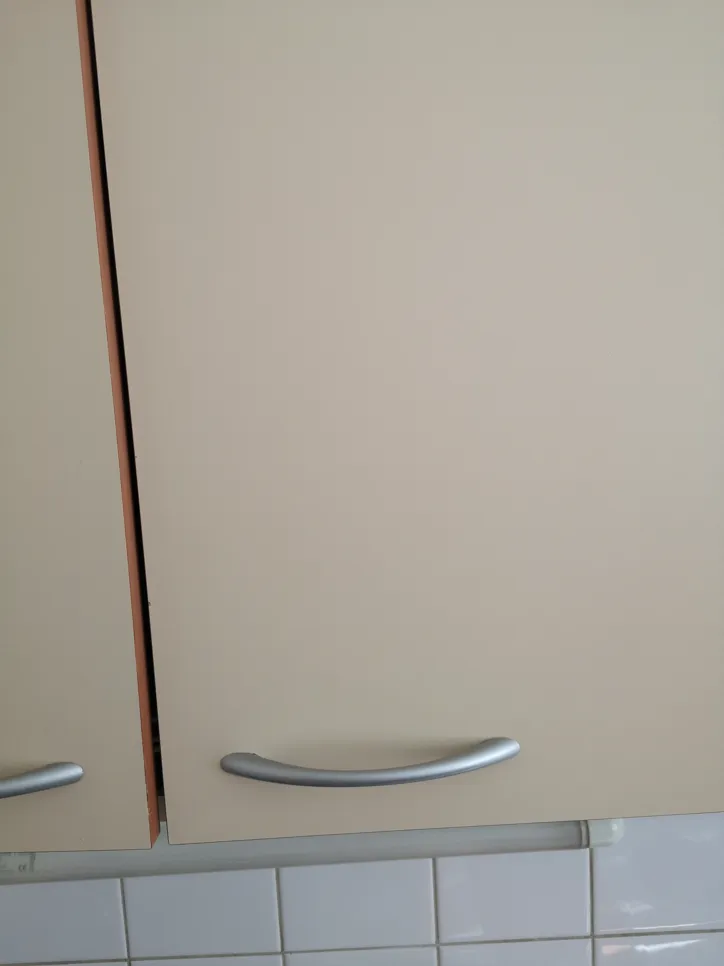 A kitchen cabinet door appears misaligned with visible gaps, highlighting potential installation issues.