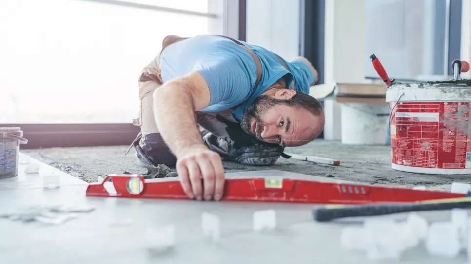 Keramičar meri in se nasmehne ob novici, da se inflacija precej pozna tudi pri cenah obrtniških storitev.