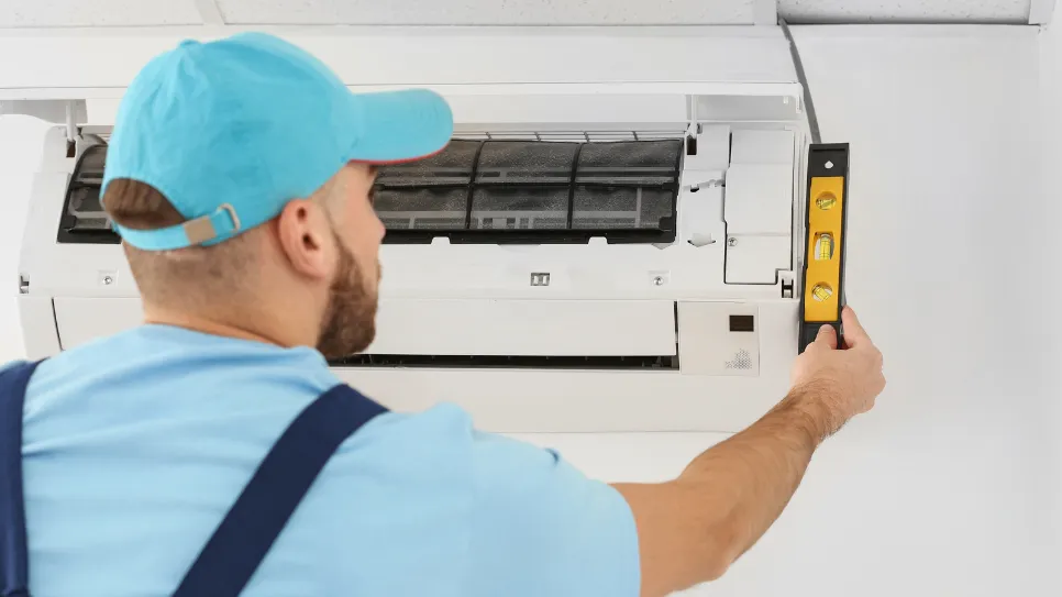 Monter namešča notranjo enoto klimatske naprave na zid.