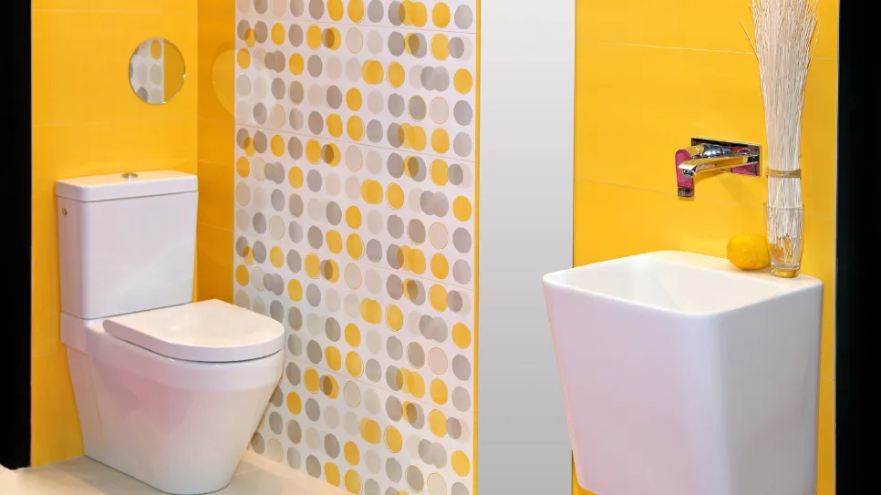 Wc školjka in umivalnik v rumeni kopalnici.