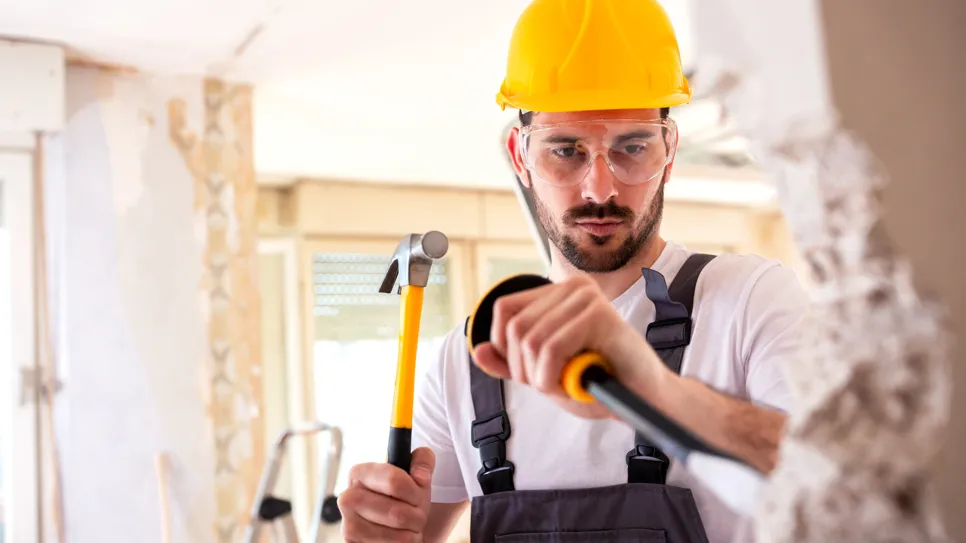 mojster z dletom na roke ruši notranji zid v hiši