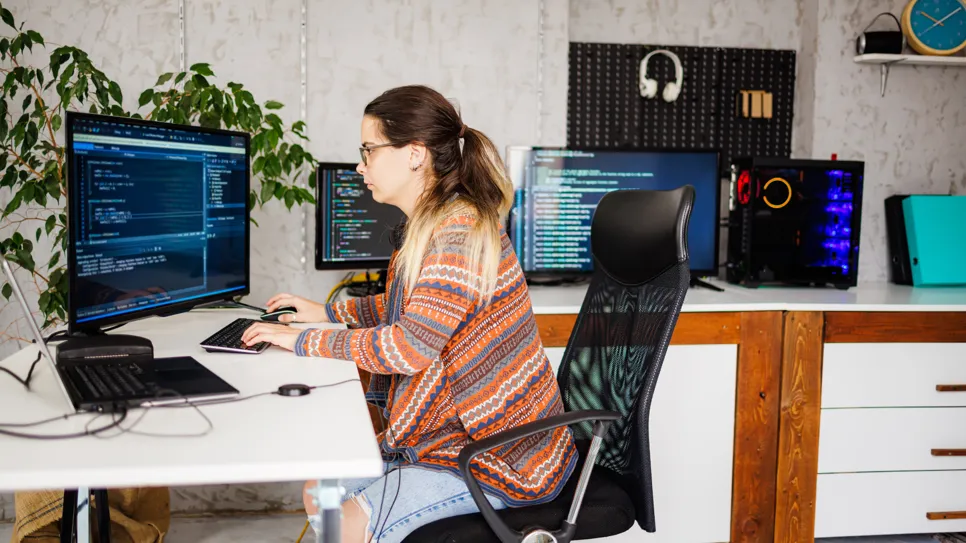 Programerka za računalnikom kodira spletno stran po meri.