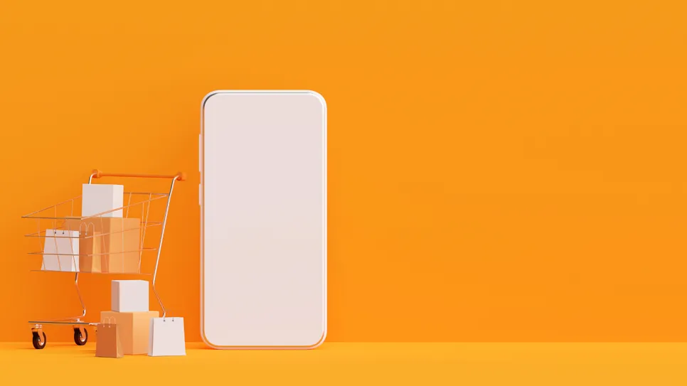 mobilni telefon in nakupovalni voziček na rumeni podlagi