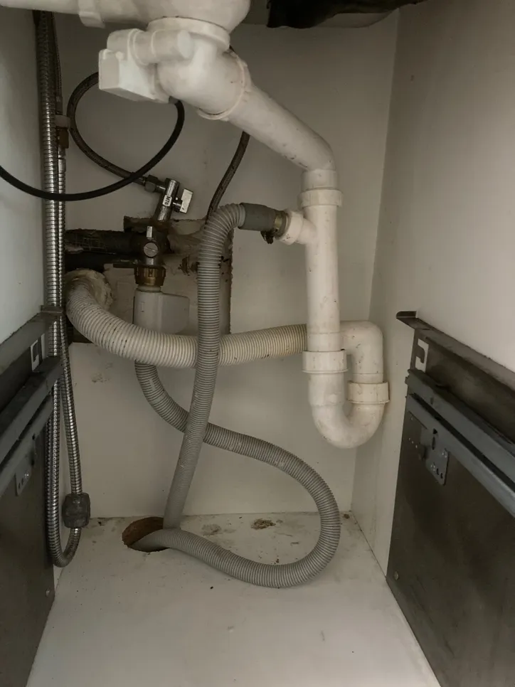 Nastavitev vodovodne instalacije pod umivalnikom, ki vključuje odtočne cevi in fleksibilno cevno povezavo.