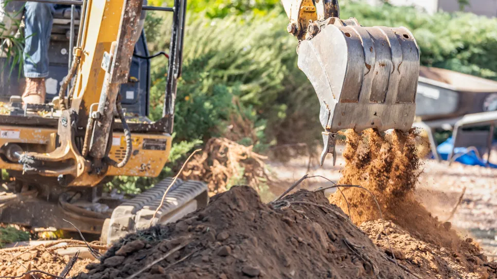 Bager v delu koplje zemljo na gradbišču.